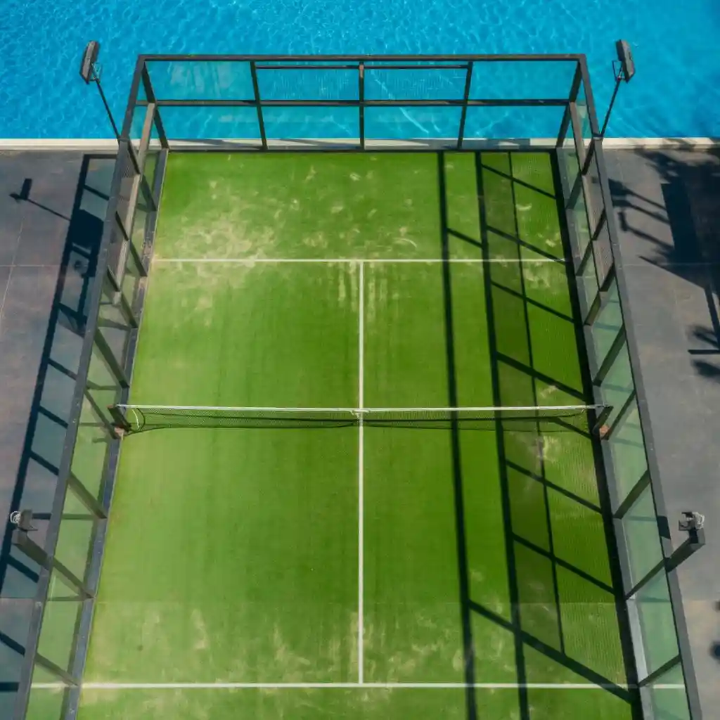 Quadra de padel com paredes de vidro e piso de grama sintética